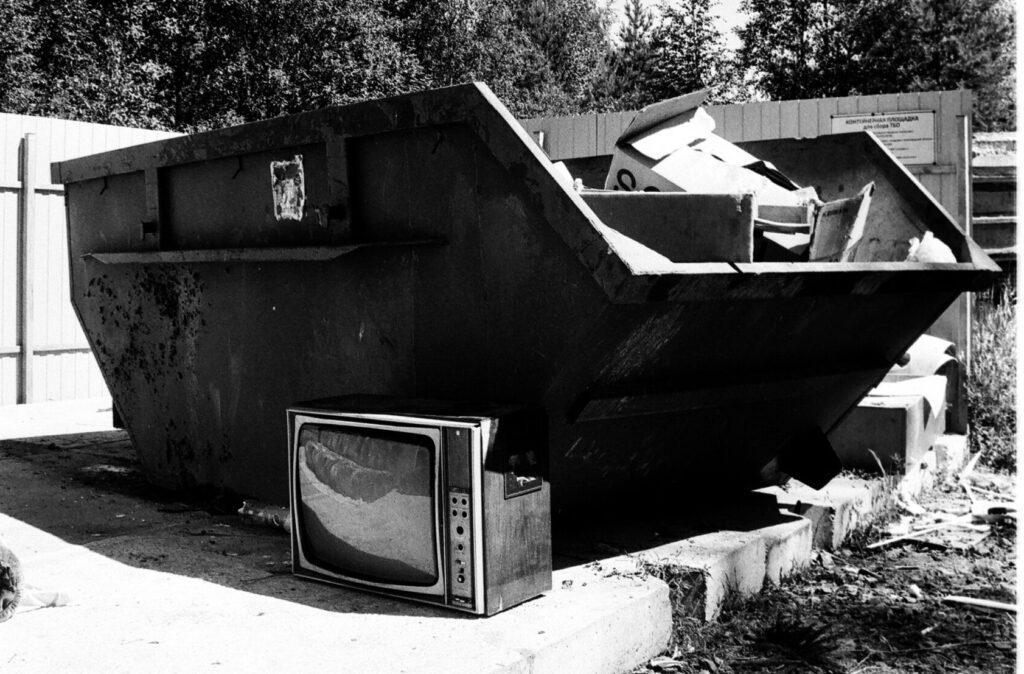 Black and white photo of a dumpster and garbage.